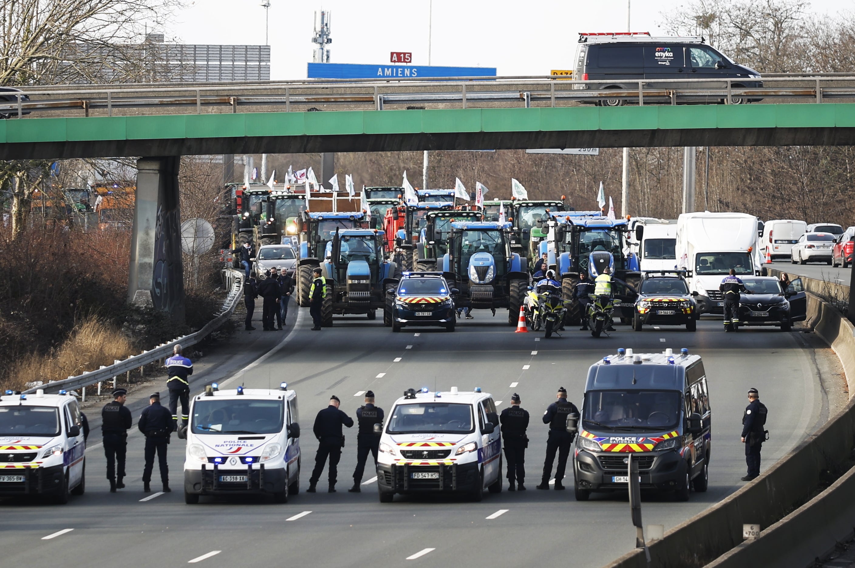 Argenteuil (Francia), 29/01/2024.- Agentes de policía vigilan decenas de tractores que participan en una manifestación en la autopista A15 cerca de Argenteuil, al norte de París, Francia, este lunes. Los agricultores franceses continúan sus protestas con bloqueos de carreteras y Manifestaciones frente a edificios estatales a la espera de una respuesta del gobierno a su solicitud de ayuda "inmediata" de varios cientos de millones de euros. EFE/YOAN VALAT