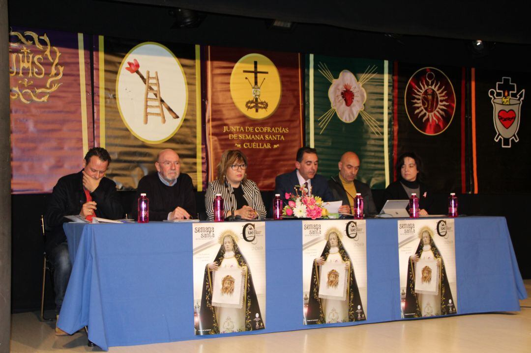 El presidente de la Junta de Cofradías, Fernando Santana, junto a la concejal Sonia Martín en el centro de la mesa, acompañados por el sacerdote Fernando Mateo y representantes de distintas cofradías de Cuéllar