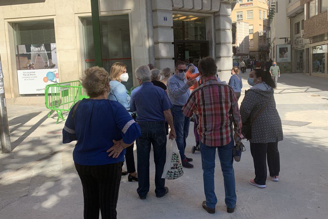 Varias personas hacen cola a las puertas de la oficina central de CajaSur en Jaén.