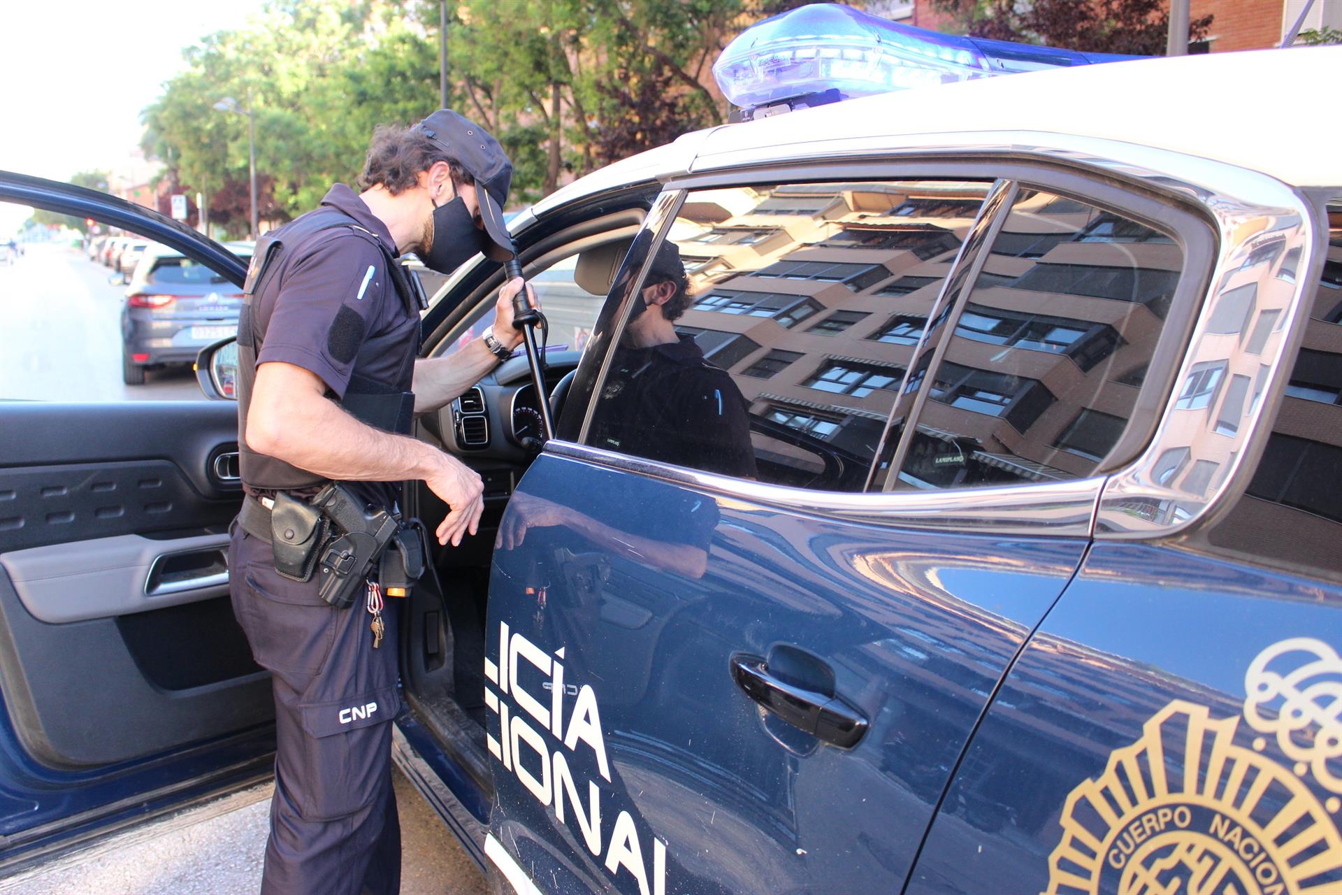 Un agente junto a un coche patrulla.