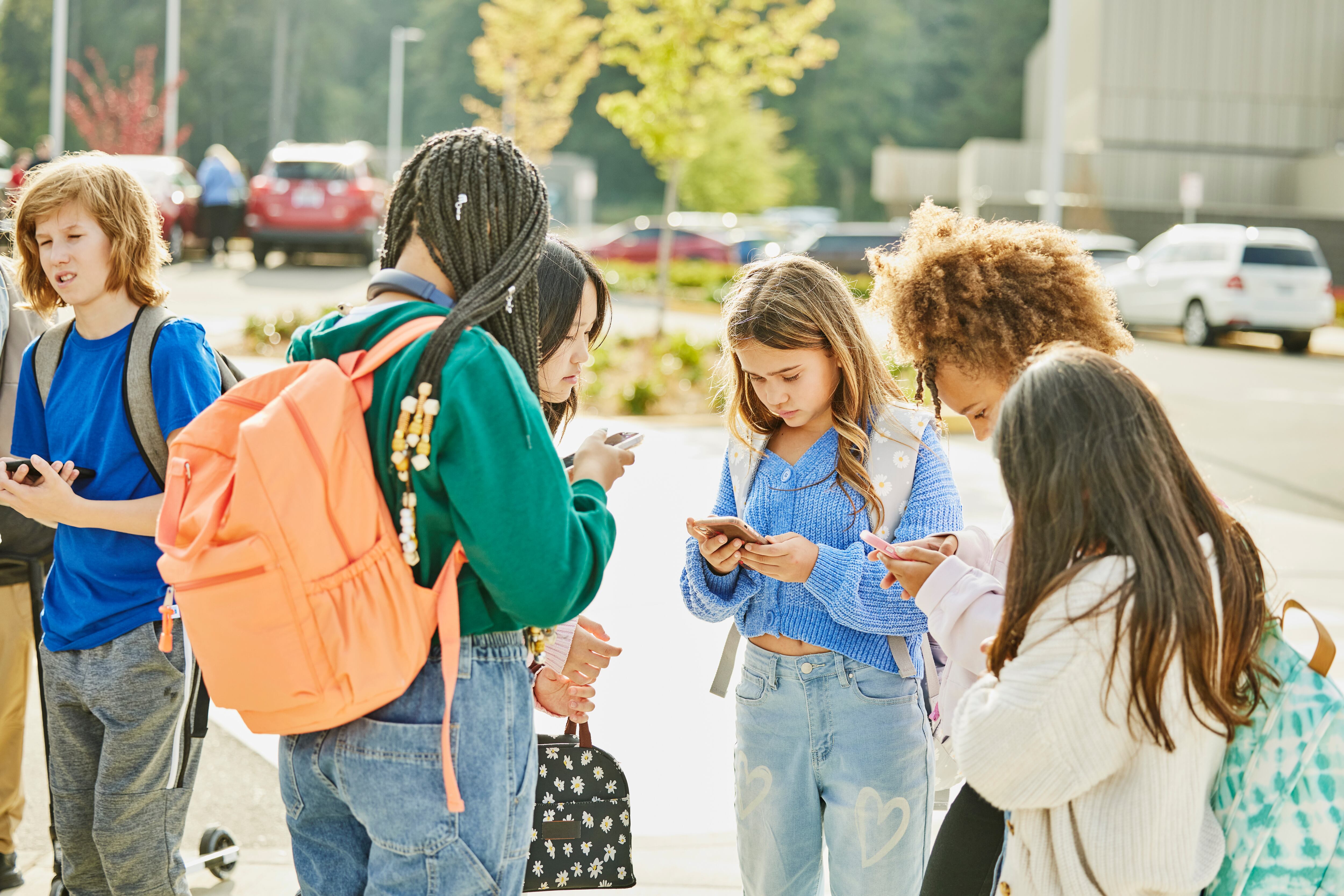 Adolescents amb un telèfon mòbil a l'entrada d'una escola