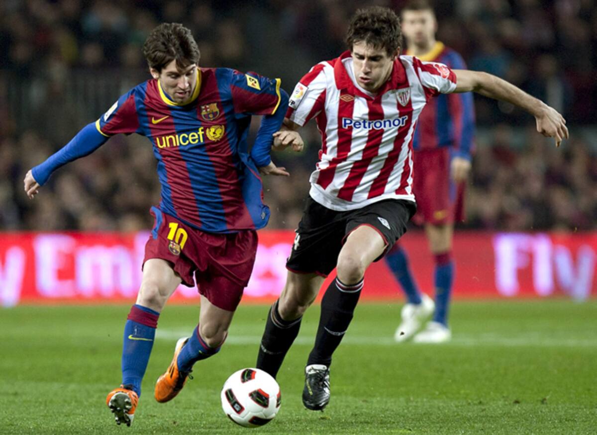 El delantero argentino del FC Barcelona Lionel Messi (i) conduce el balón presionado por el mediocentro del Athletic de Bilbao Javi Martínez durante el partido correspondiente a la vigésimo cuarta jornada del Campeonato Nacional de Liga de Primera Divisió