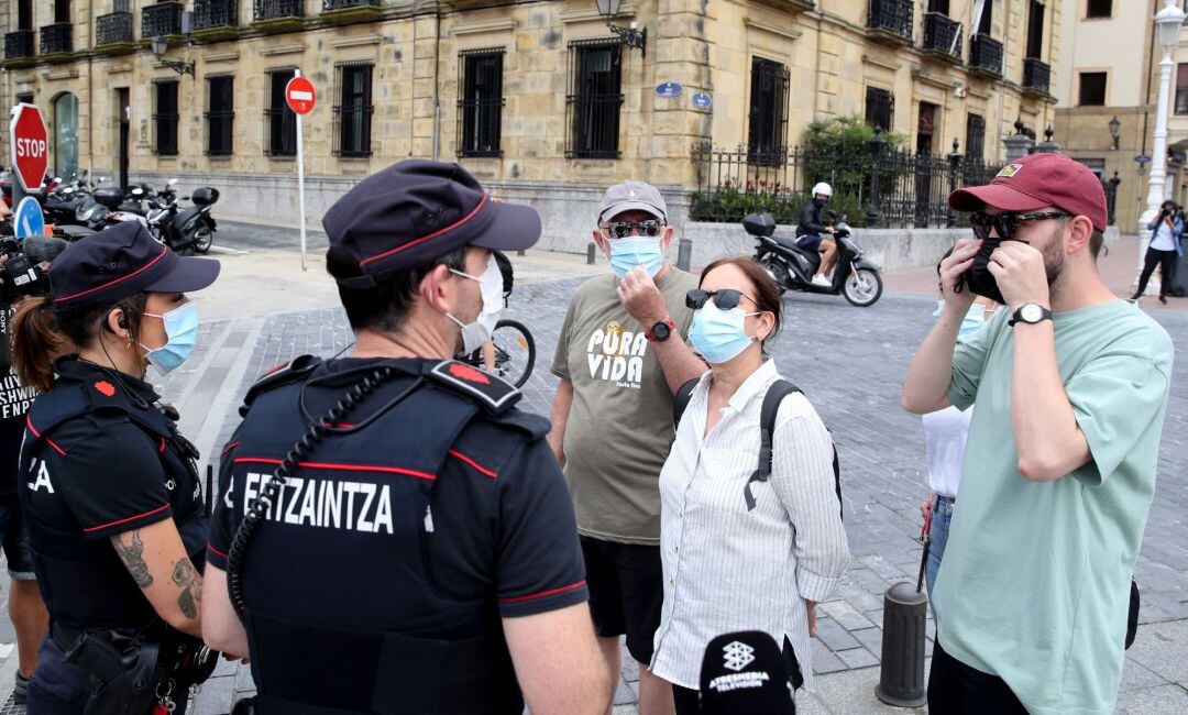 Agentes de la Ertzaintza informan a unos turistas de la necesidad de usar la mascarilla en caso de no ser convivientes. Responsables de la Ertzaintza y de la Guardia Municipal han dado cuenta este viernes en San Sebastián del operativo conjunto para el cu