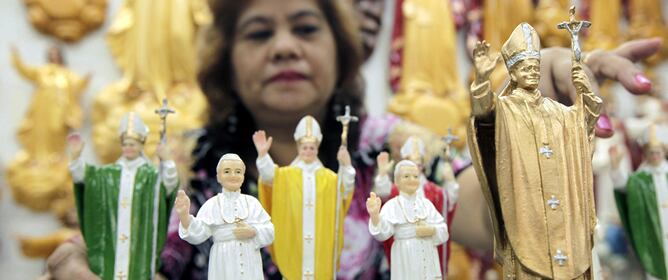 Una mujer vende estatuillas del papa Juan Pablo II en una tienda en Manila (Filipinas) hoy, sábado, 30 de abril de 2011