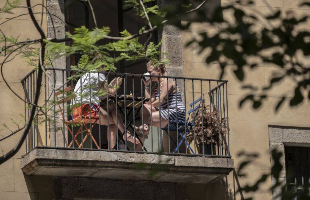 Dos mujeres sentadas en el balcón de una vivienda