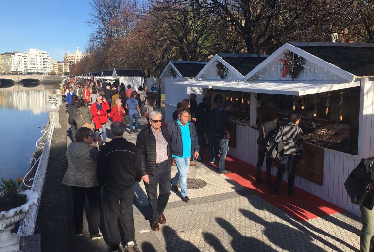 Varias personas visitan el gran mercado de Navidad de San Sebastián en su primer día de apertura.