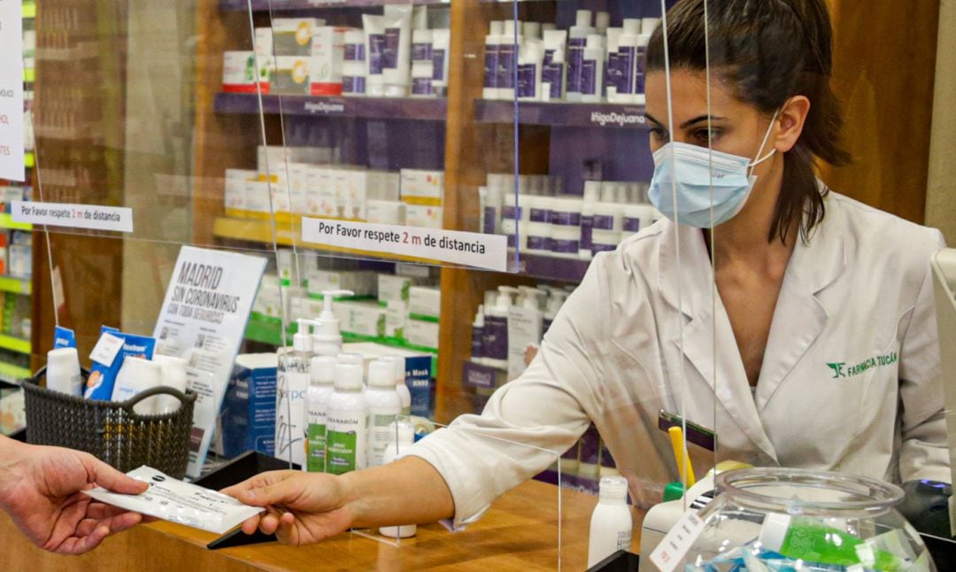 Una farmacéutica entrega una mascarilla