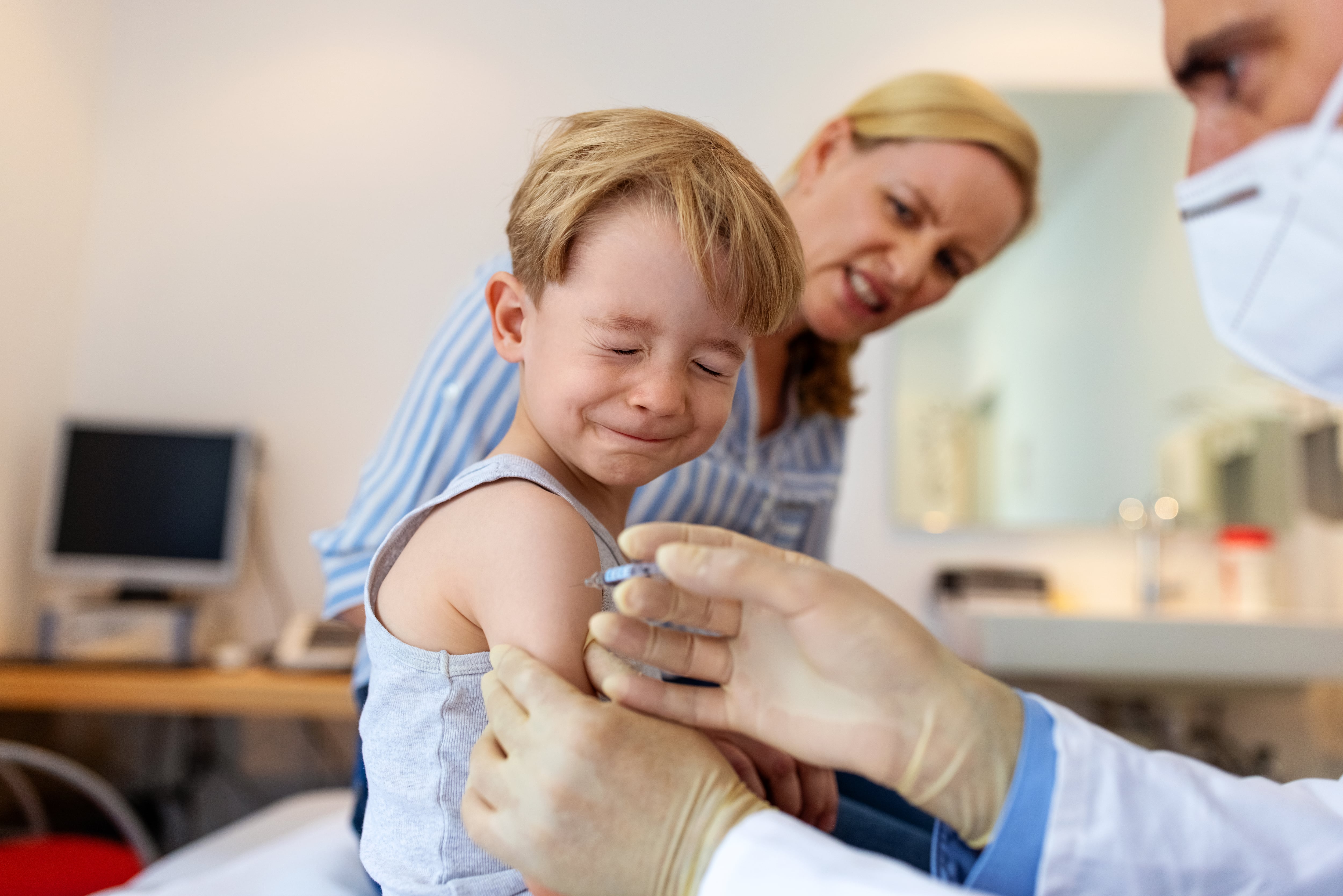 Un niño cierra los ojos ante la vacuna.