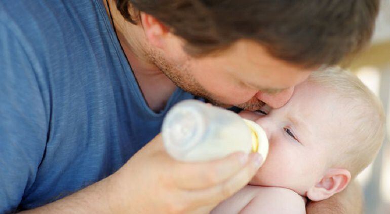 Un padre da el biberón a su hijo