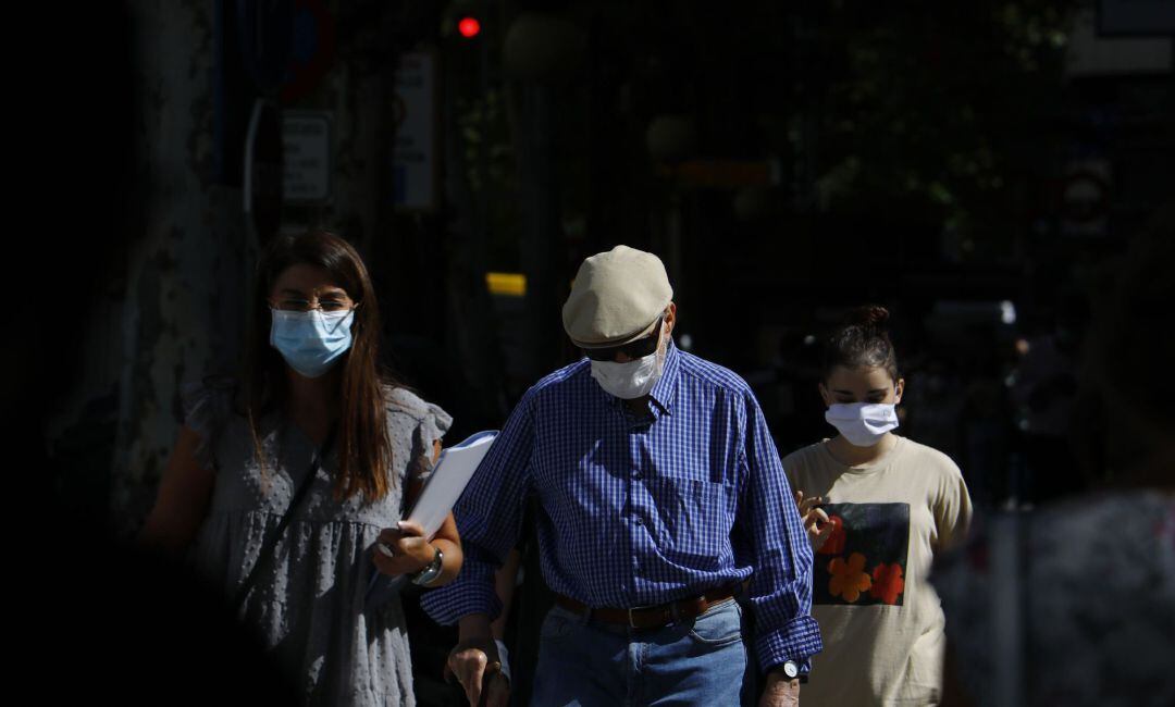 Personas con mascarilla caminan por una calle 