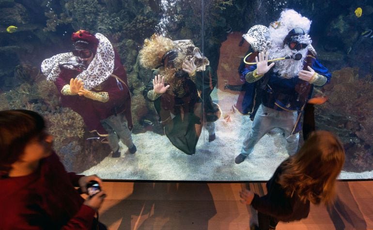  Los Reyes Mayos saludan a los niños, mientras bucean entre especies marinas, en el Oceanográfic de la Ciudad de las Ciencias en Valencia. 