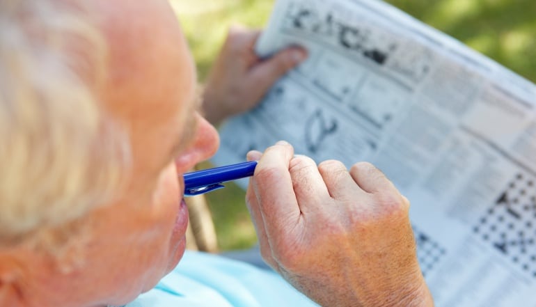 Imagen de un señor completando los pasatiempos de un periódico.