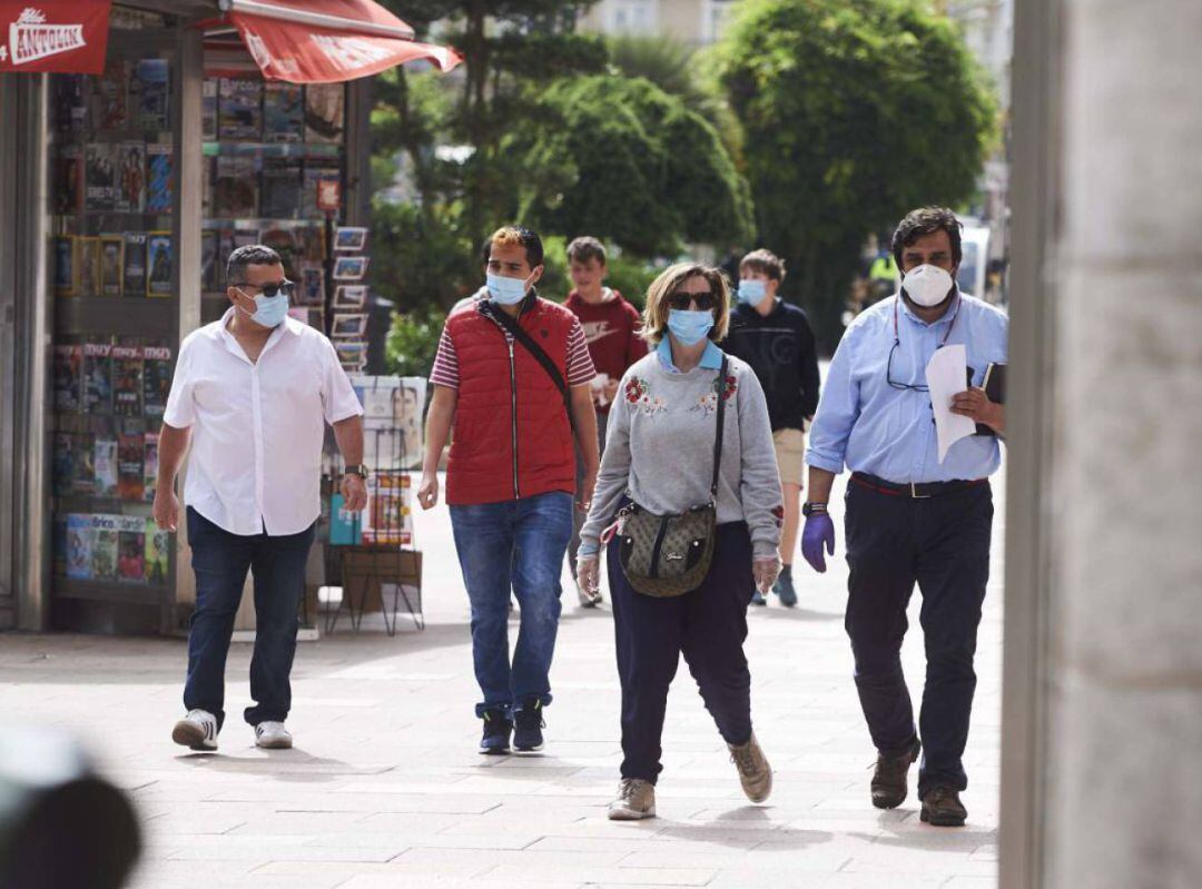 Gente paseando por la calle con mascarilla.