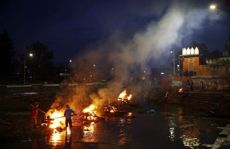 Un cura incinera los restos mortales de varias víctimas del seísmo de Nepal, en el centro de incineraciones de Pashupat, Katmandú.