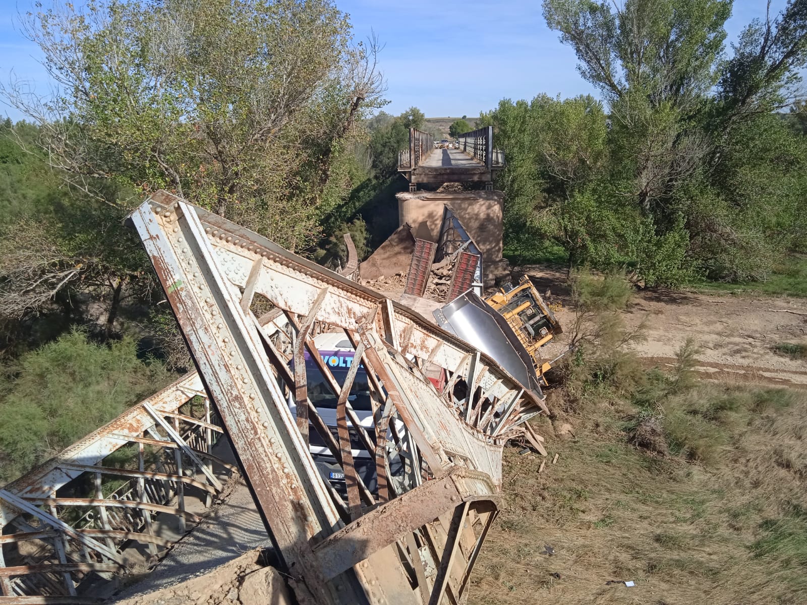 En la imagen, la parte del puente colapsada sobre el cauce del río, con el camión góndola y la niveladora de terrenos que transportaba