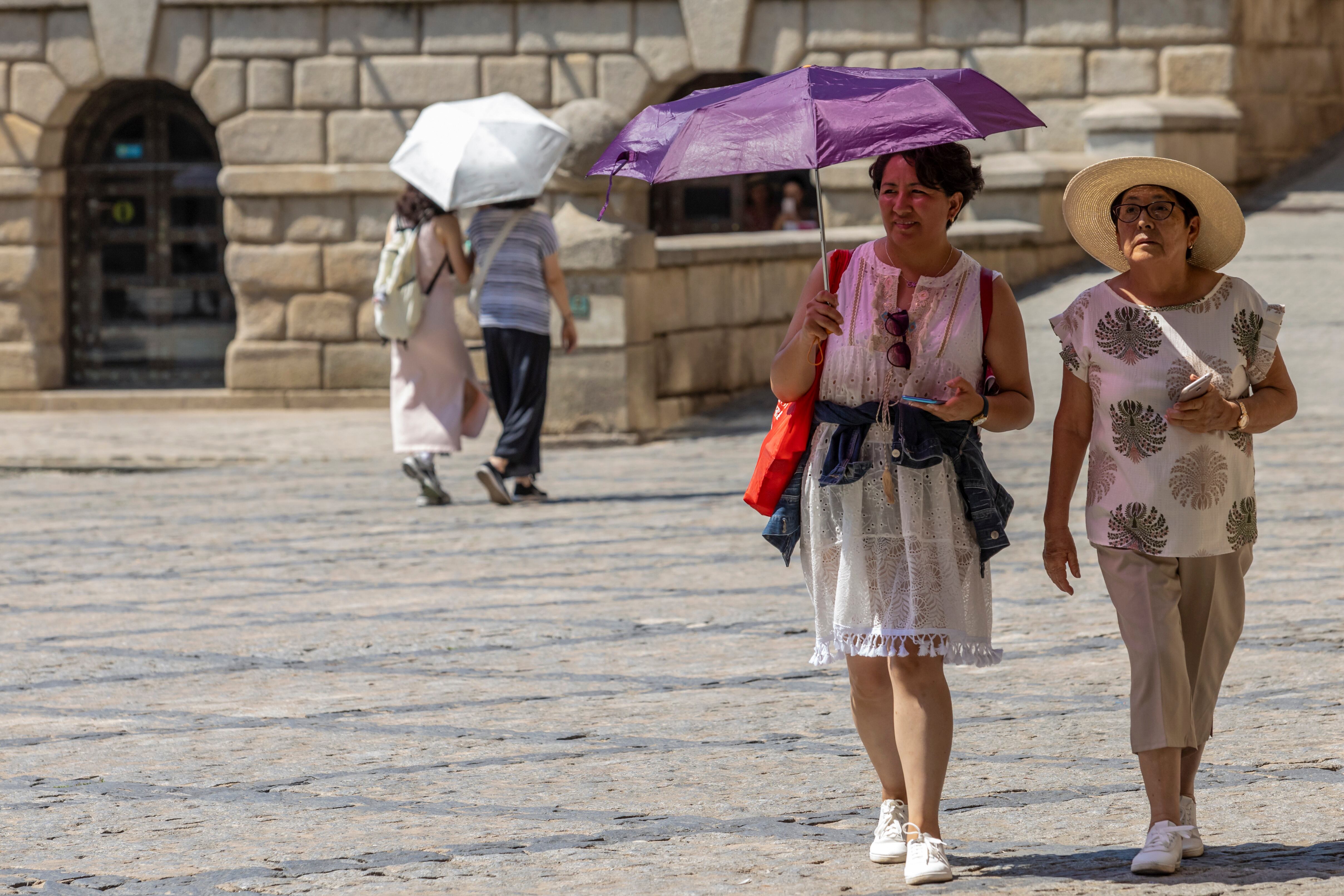 Varias personas se protegen del sol mientras pasean. EFE/ Ángeles Visdómine