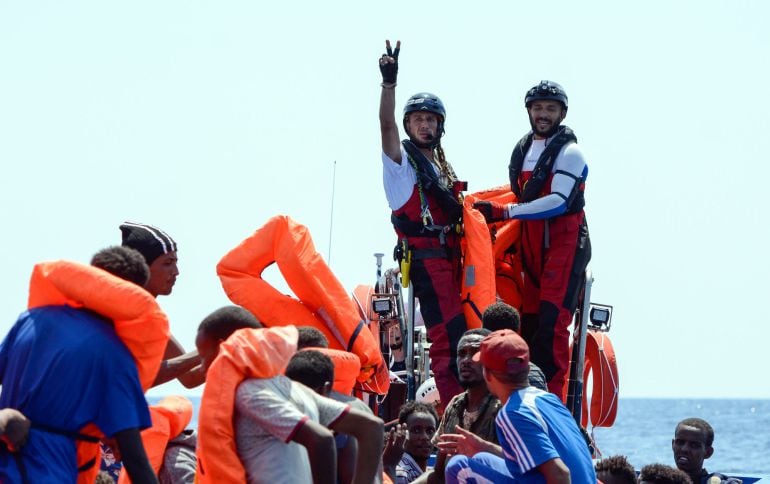 Dos tripulantes del barco de rescate ayudando a una embarcación a la deriva