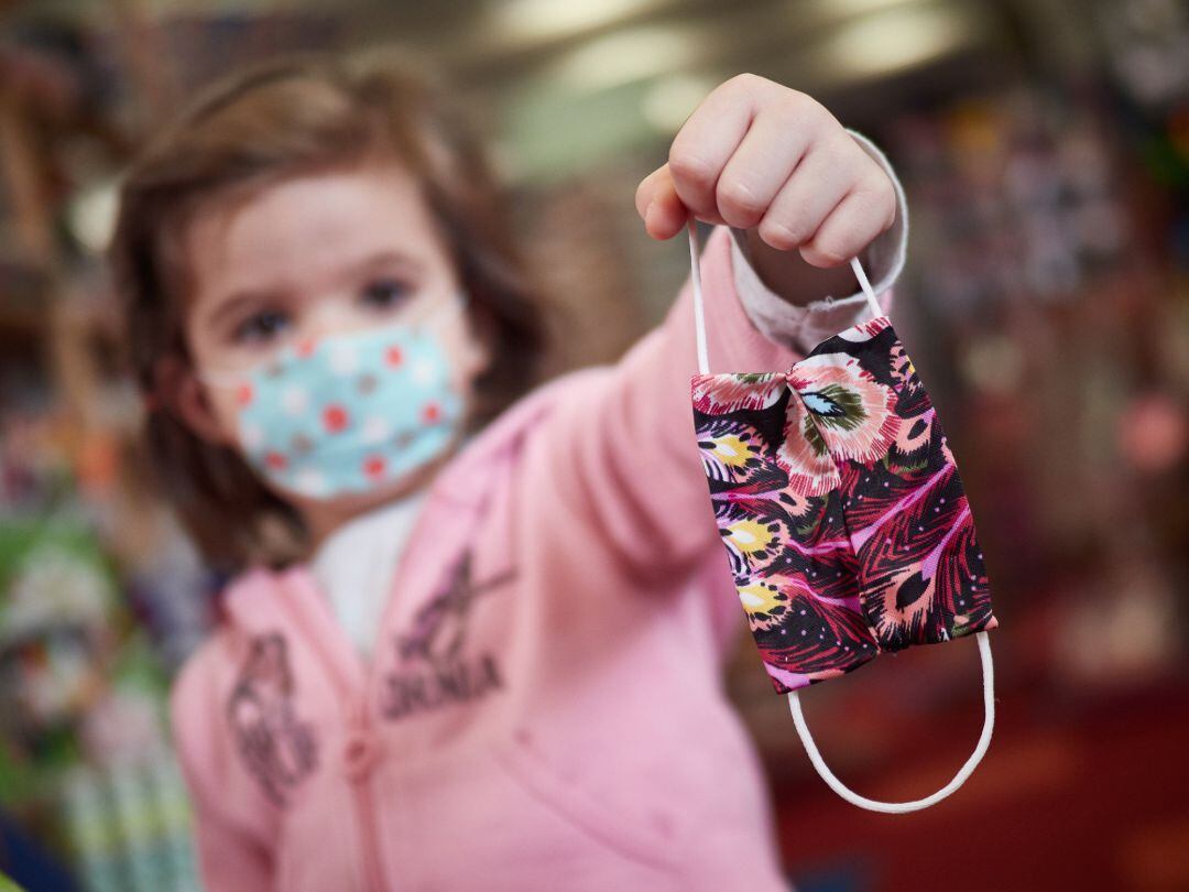 Una niña muestra una mascarilla infantil