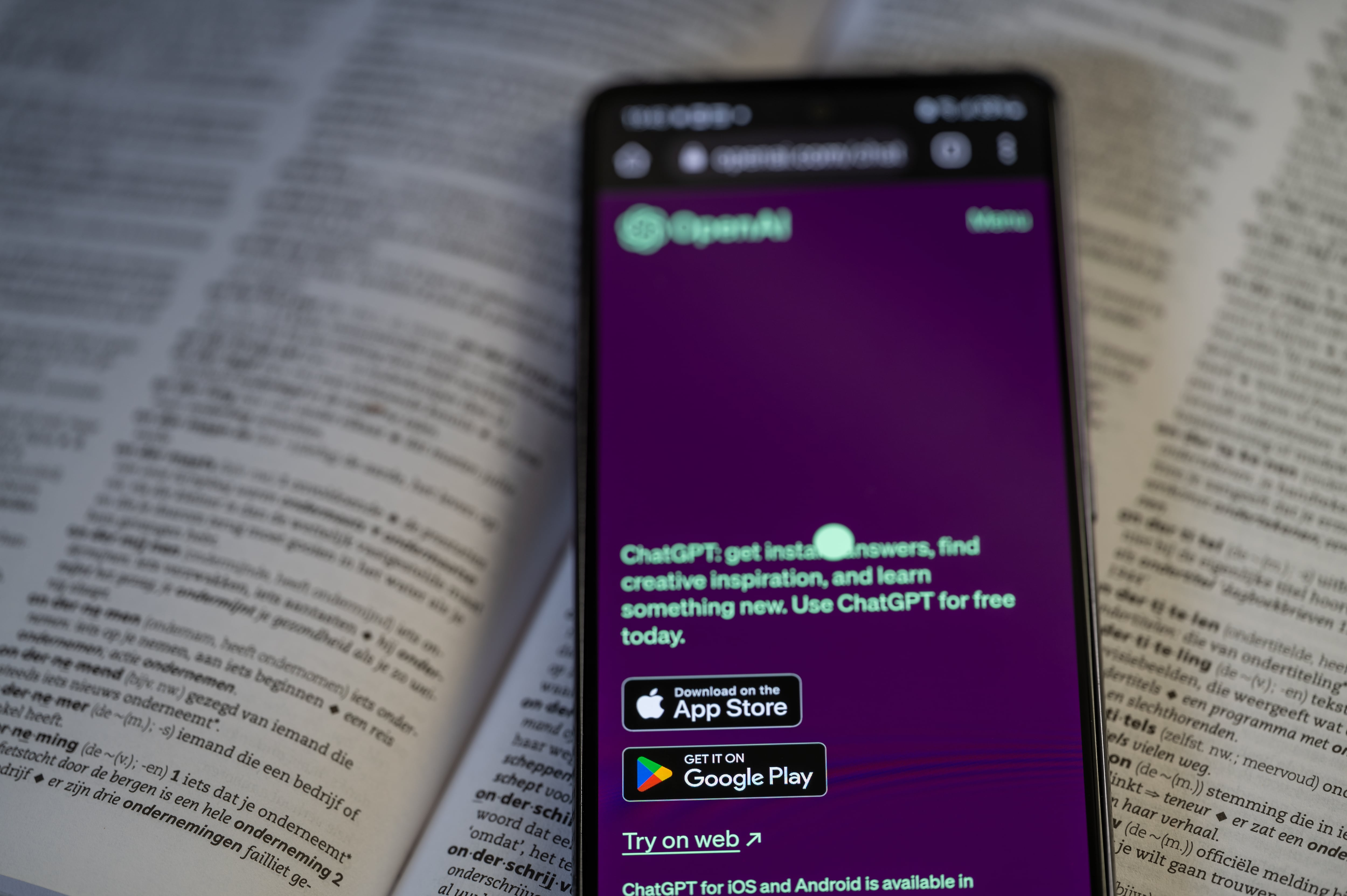 Open Ai mobile app displayed on a smart phone with a dictionary book, seen in this photo illustration. On 20August 2023 in Brussels, Belgium.  (Photo by Jonathan Raa/NurPhoto via Getty Images)