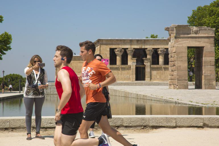 Dos jóvenes corren frente al Templo de Debod