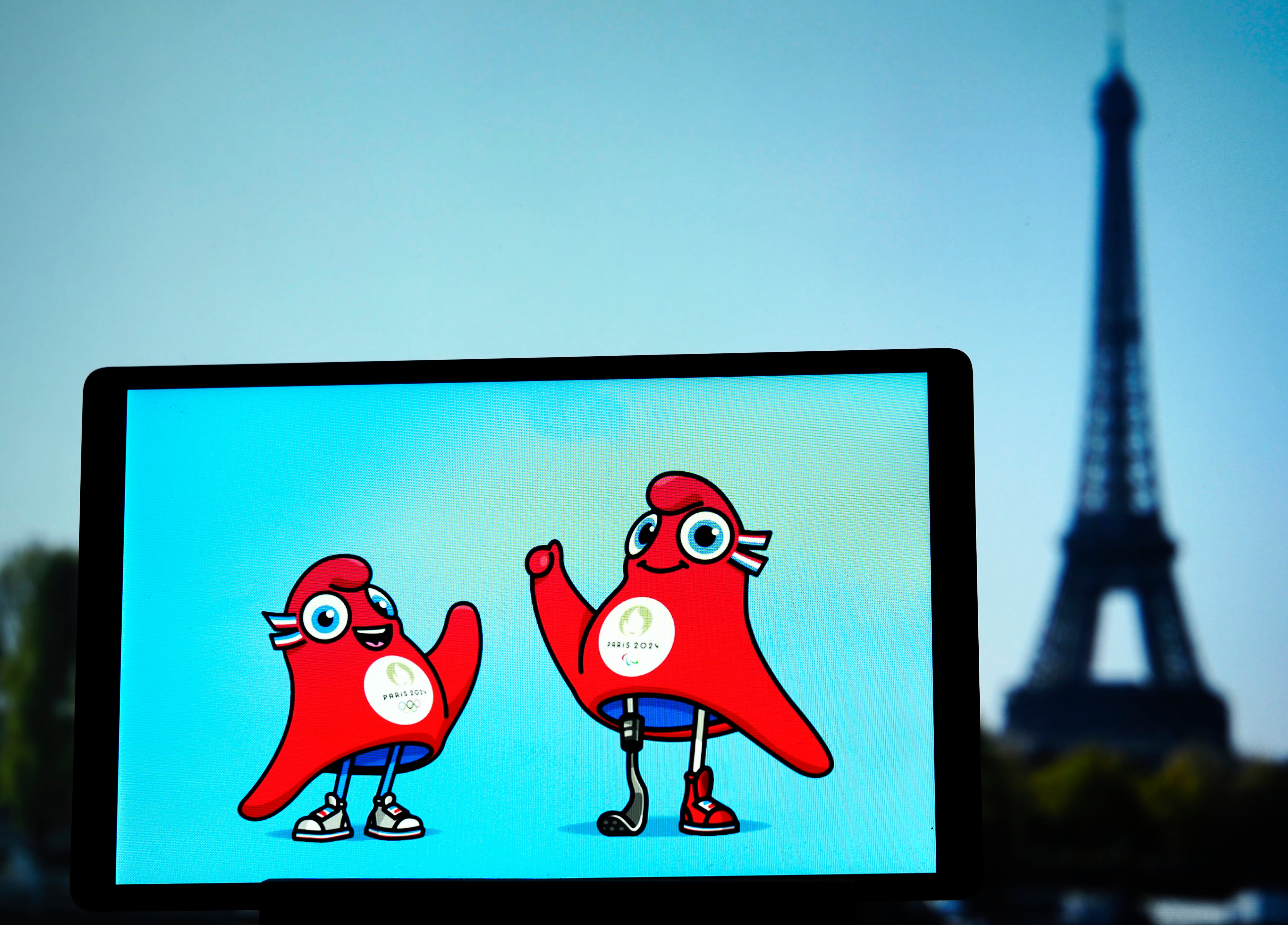 Ilustración de Phryge olímpica y Phryge paralímpica, mascotas de los Juegos de París 2024, con la Torre Eiffel de fondo. (Photo Illustration by Igor Golovniov/SOPA Images/LightRocket via Getty Images)