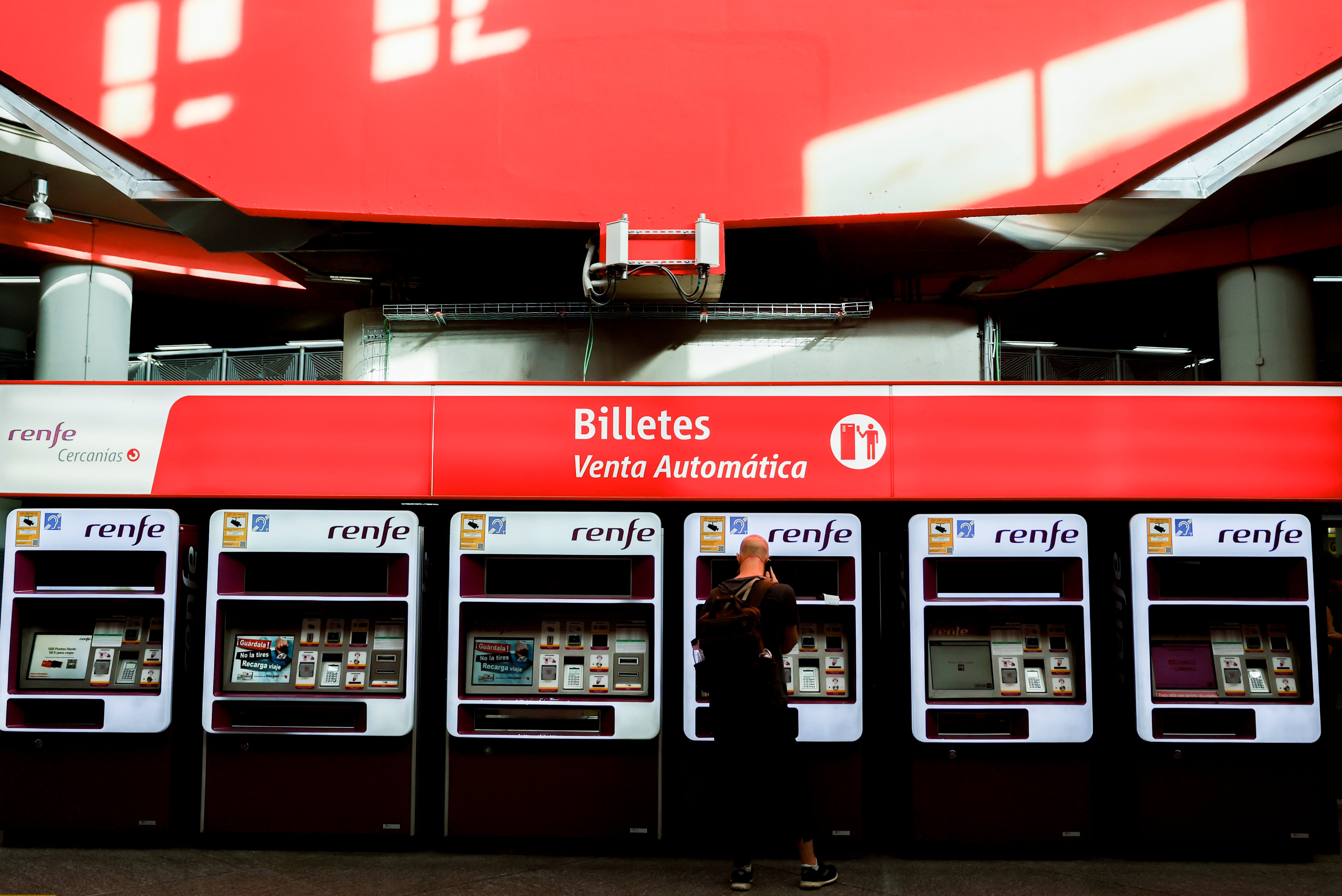 Viajeros gestionan la compra de sus abonos en máquinas expendedoras de billetes en una estación de Cercanías de Madrid.