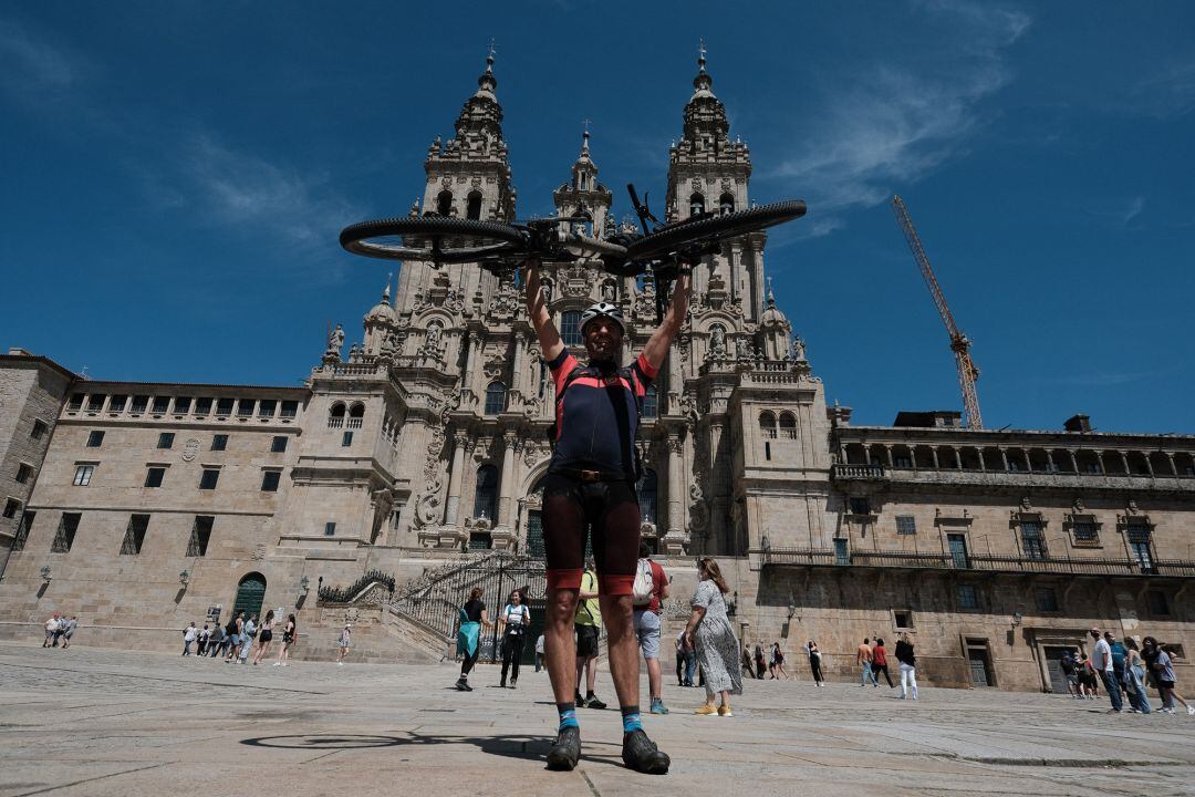 Un peregrino Portugués levanta su bicicleta al finalizar el Camino de Santiago, frente a la Catedral de Santiago,