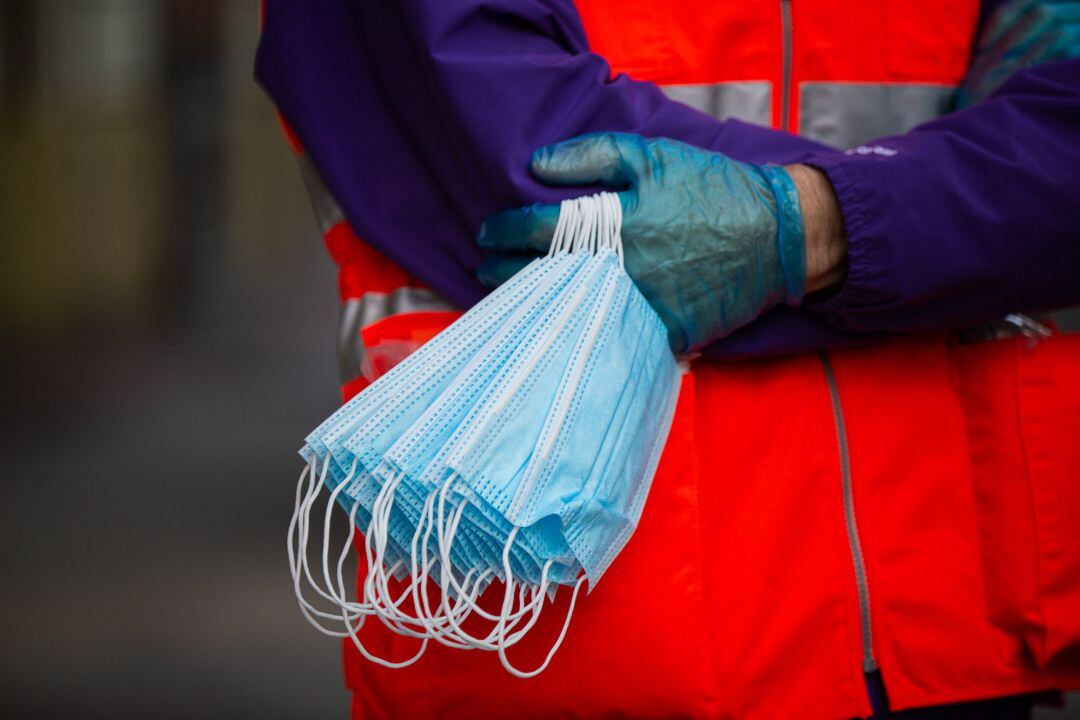 Un trabajador de Cruz Roja sostiene mascarillas para entregarlas a usuarios de transporte público de Vitoria-Gasteiz el día en el que se reactiva la actividad laboral no esencial en País Vasco