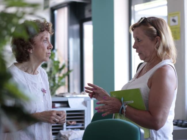 Charo (izquierda) atendiendo a una residente en la recepción