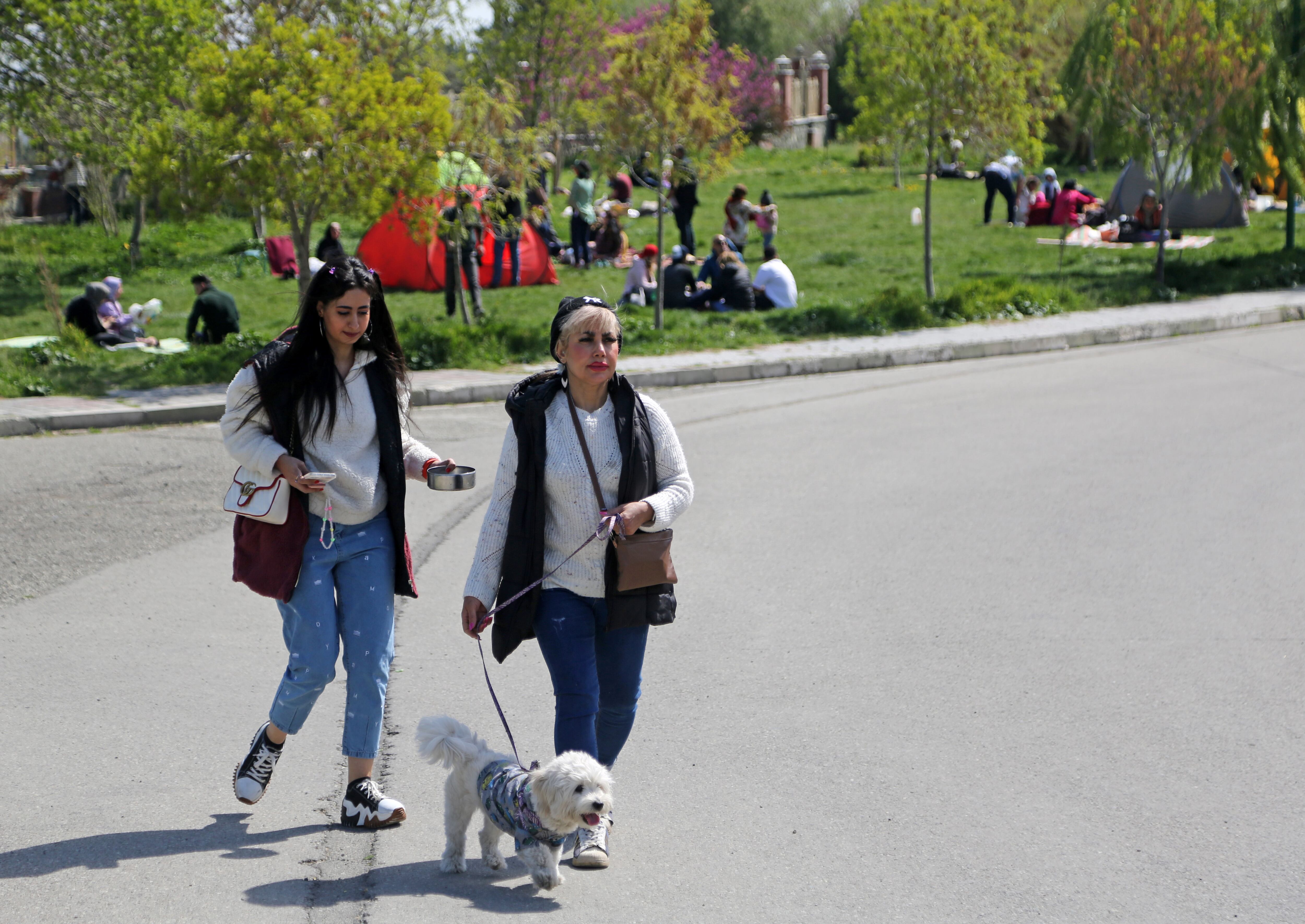 Dos personas pasean a su perro en un parque el 2 de abril de 2023 en Teherán, Irán. Fatemeh Bahrami/Agencia Anadolu.