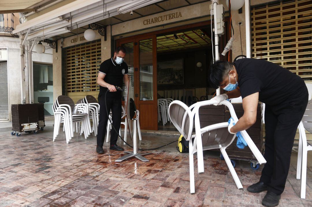 Trabajadores de la cafetería Central ubicada en la Plaza de La Constitución, en Málaga se afanan en la limpieza de los enseres de la terraza a consecuencia del virus COVID-19.