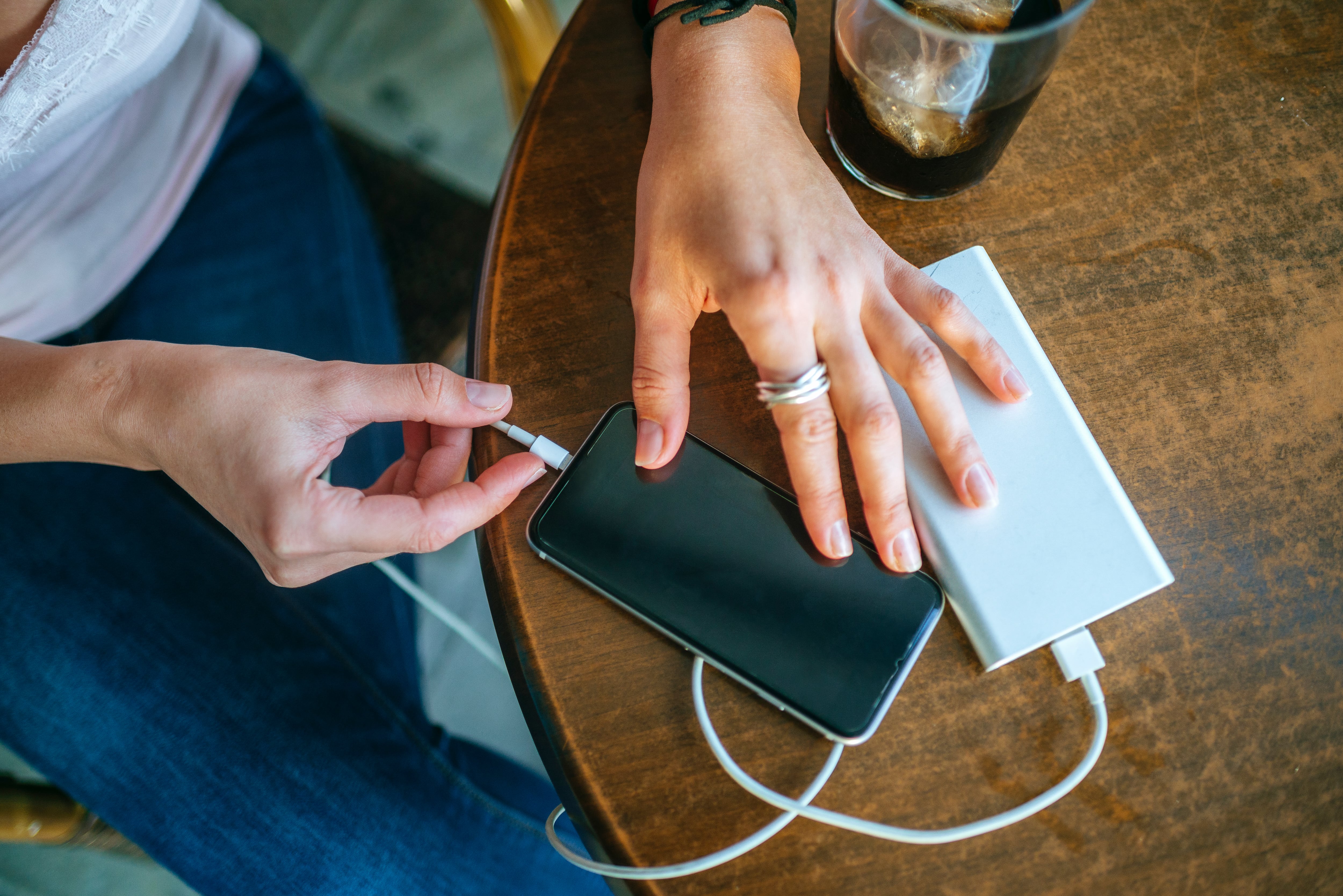 Una mujer carga su teléfono móvil en una cafetería.