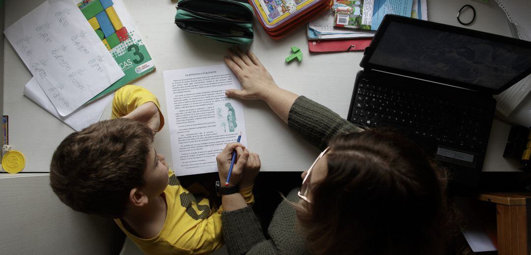 Un niño estudia y hace los deberes en casa con la ayuda de su madre