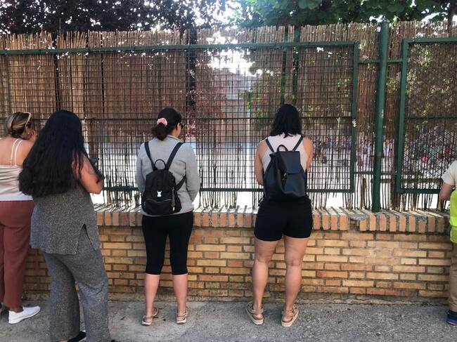 Madres, mirando a sus hijos a través de la valla