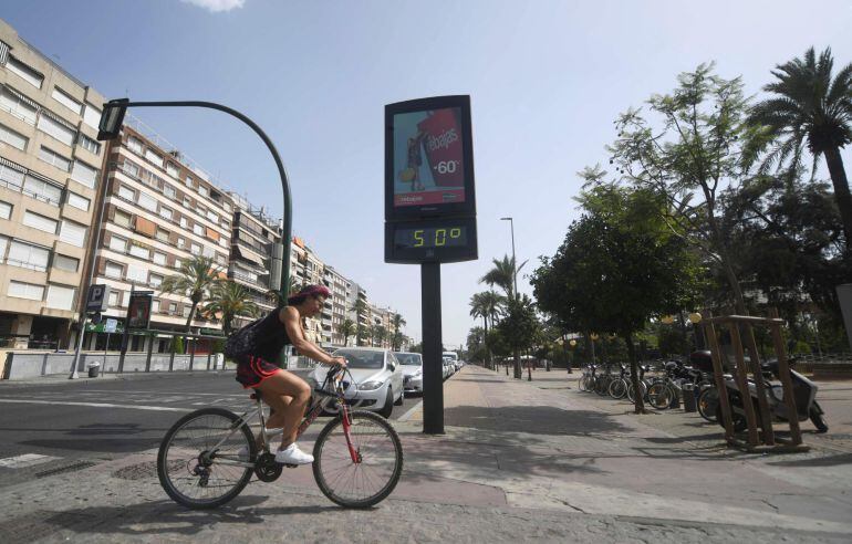 Un ciclista pasa junto a un termómetro que marca 50 grados en Córdoba, en una jornada marcada por la ola de calor que afecta a toda la Península.