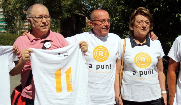 Tres membres de l'ANC i Òmnium de Lleida que mostren o porten posada la samarreta de la Diada.