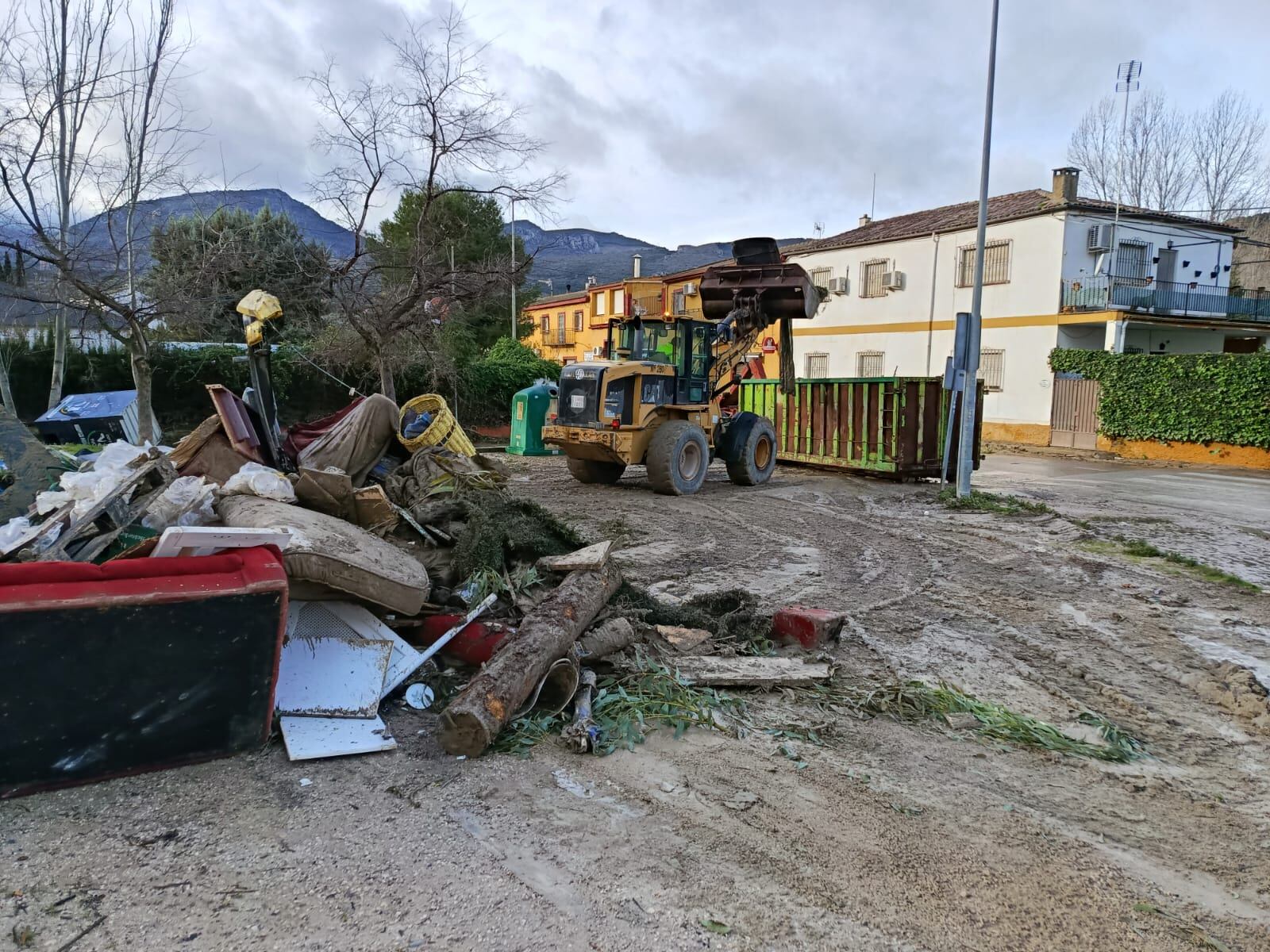 Una grúa retira troncos y otros materiales afectados por una riada en los Puentes de Jaén.