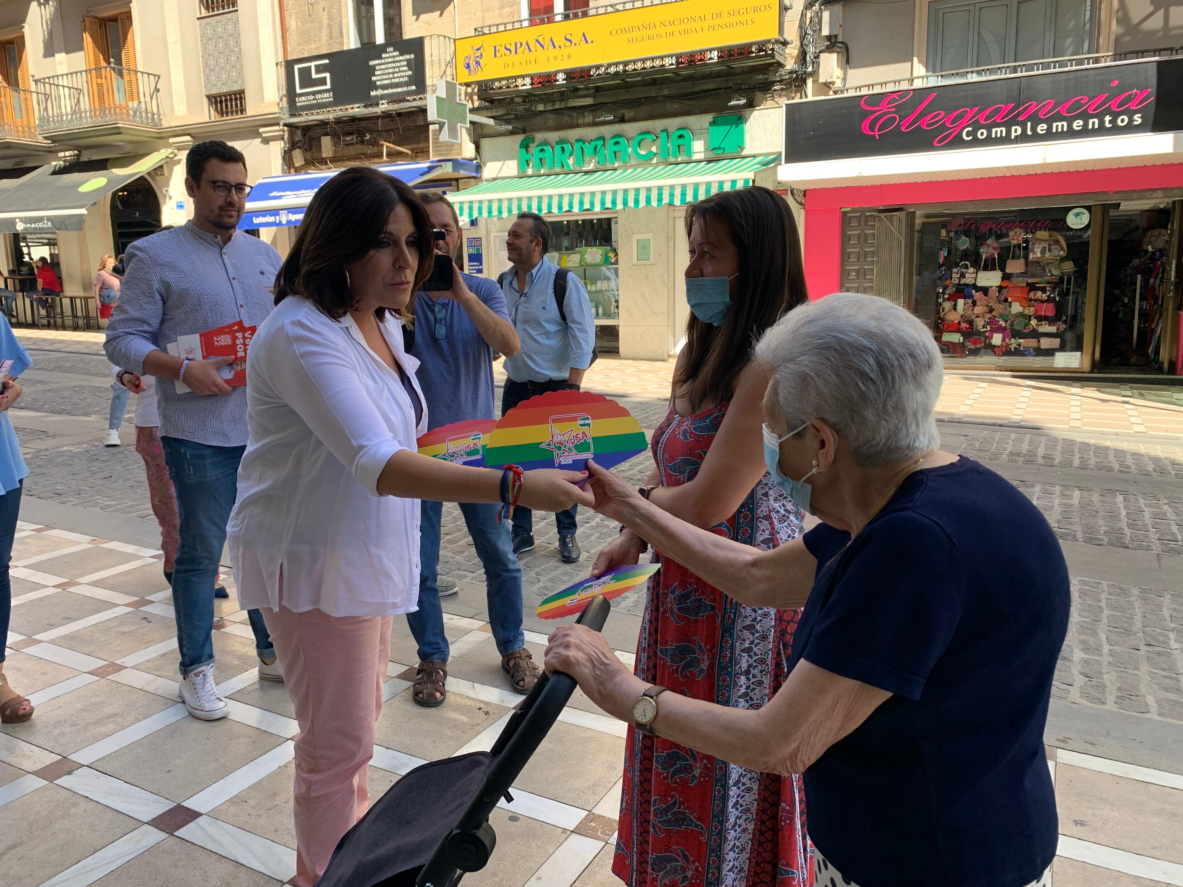 La candidata del PSOE-A por Jaén, Ángeles Férriz, entrega un abanico arco iris a una mujer durante el paseo electoral que ha realizado este viernes.