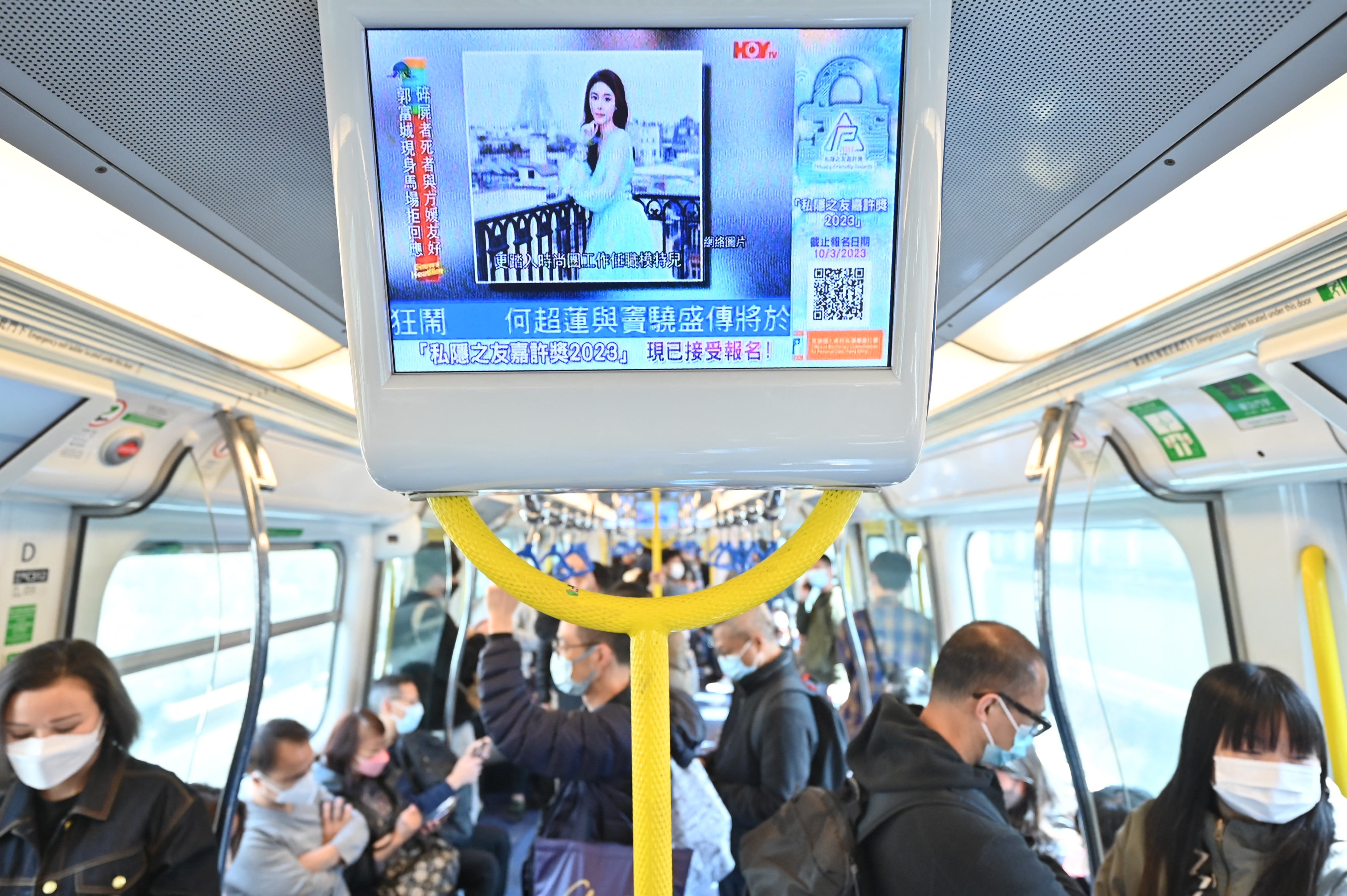 La gente mira una pantalla en un tren de Hong Kong que muestra noticias sobre la muerte de la modelo e influencer Abby Choi