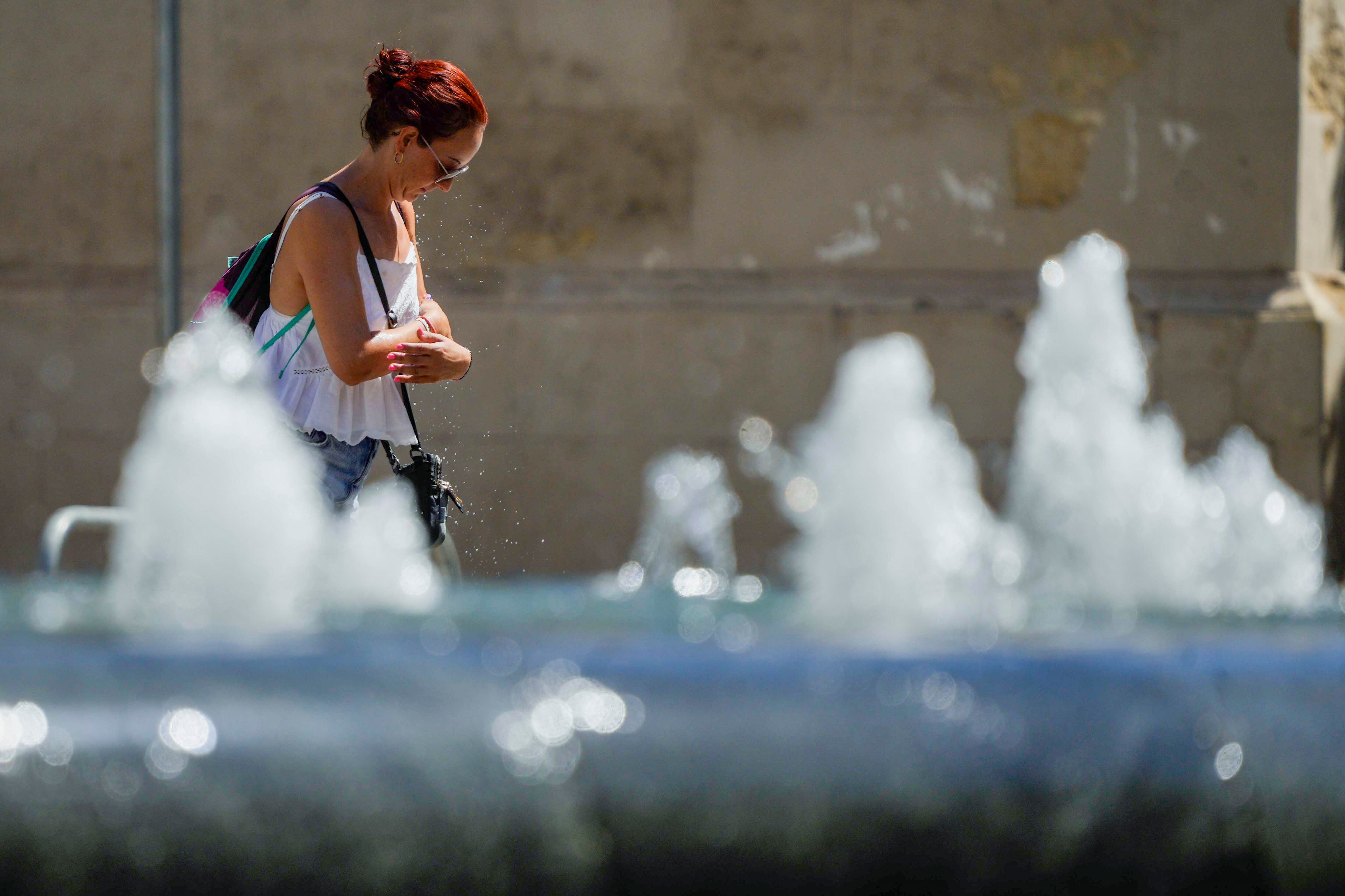 Una mujer se refresca en una fuente del centro de Córdoba