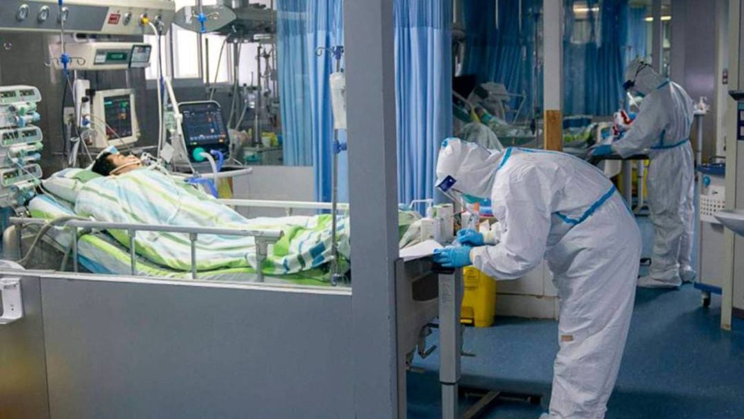 En foto, un médico asiste a un paciente en la unidad de cuidados intensivos del hospital Zhongnan, en Wuhan