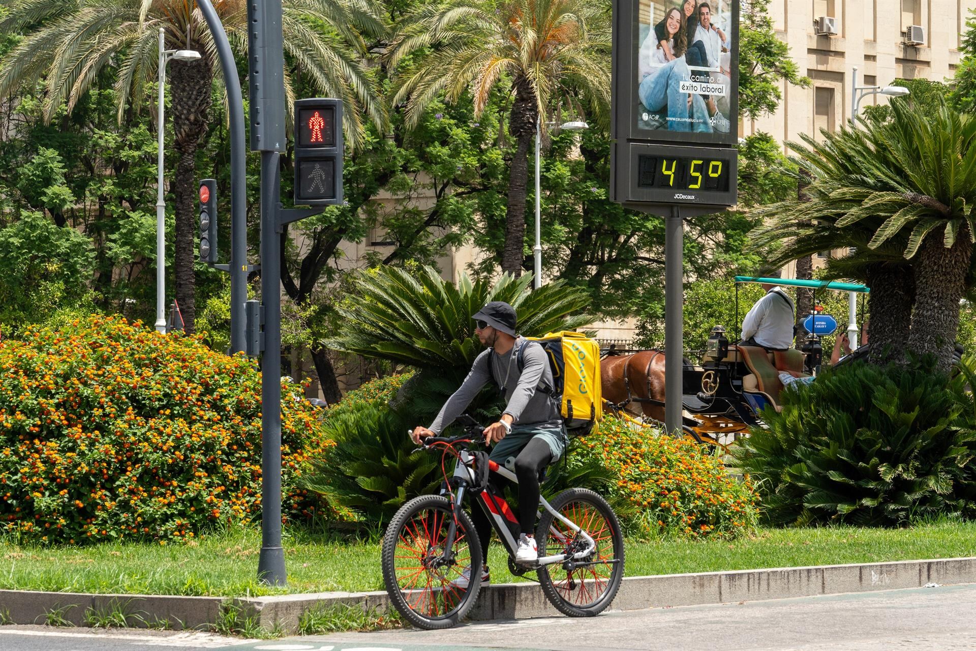 Un termómetro marca 45 grados a las 14:00 de la tarde junto a un trabajador de Glovo en bicicleta. Imagen de archivo. - Francisco J. Olmo - Europa Press - Archivo