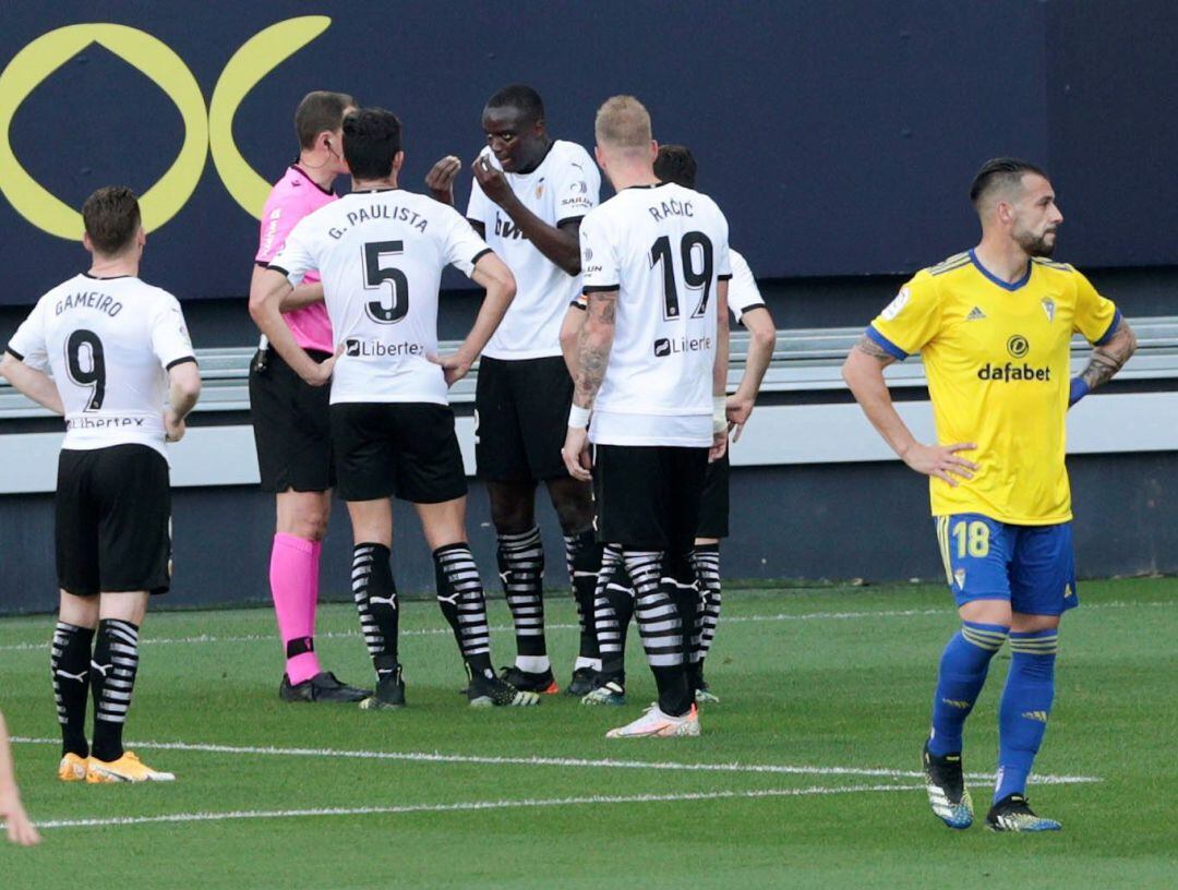 GRAF7476. CÁDIZ. El defensa del Valencia Mouctar Diackhaby (3-d) conversa con el árbitro Medié Jiménez (2-i) momentos antes de abandonar el terreno de juego el equipo valencianista, durante el partido de Liga en Primera División ante el Cádiz que disputan