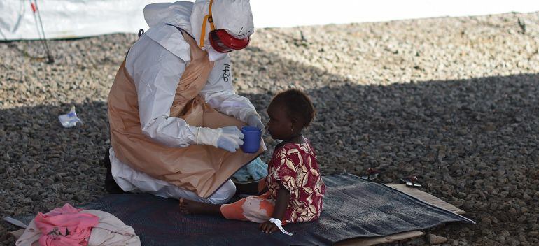 TOPSHOTS An health worker wearing protective equipment gives to drink to an Ebola young patient at Kenama treatment center run by the Red cross Society on November 15, 2014. Ebola-hit Sierra Leone faces social and economic disaster as gains made since th