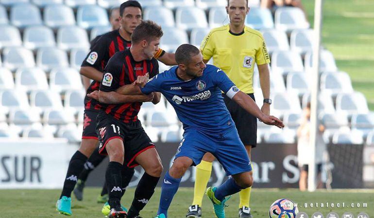 Mehdi Lacen, capitán del Getafe C.F., protege el balón ante el acoso de dos jugadores del F.C. Reus Deportiu