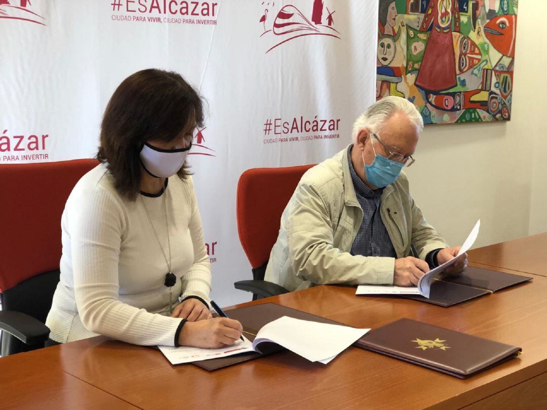 La alcaldesa de Alcázar de San Juan, Rosa Melchor, y el representante de Cáritas, Jesús Guzmán, durante la firma del convenio de colaboración