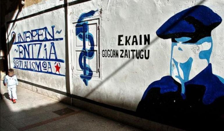 Un niño pasea frente a un mural pintado del anagrama de ETA.
