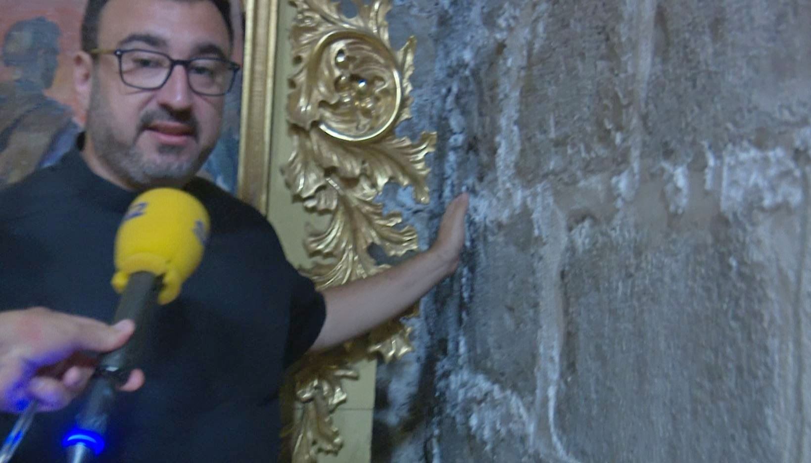 Paco Llorens pasa la mano por un muro de una capilla de la Seu afectada por el salitre que expulsa la argamasa que junta los bloques de piedra