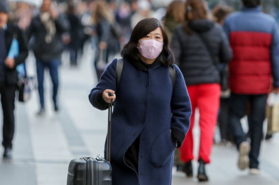  Una mujer asiática pasea con una mascarilla protectora, mientras las farmacias registran una alta demanda de estas por parte de ciudadanos chinos tras el coronavirus, en Madrid (España), a 30 de enero. 