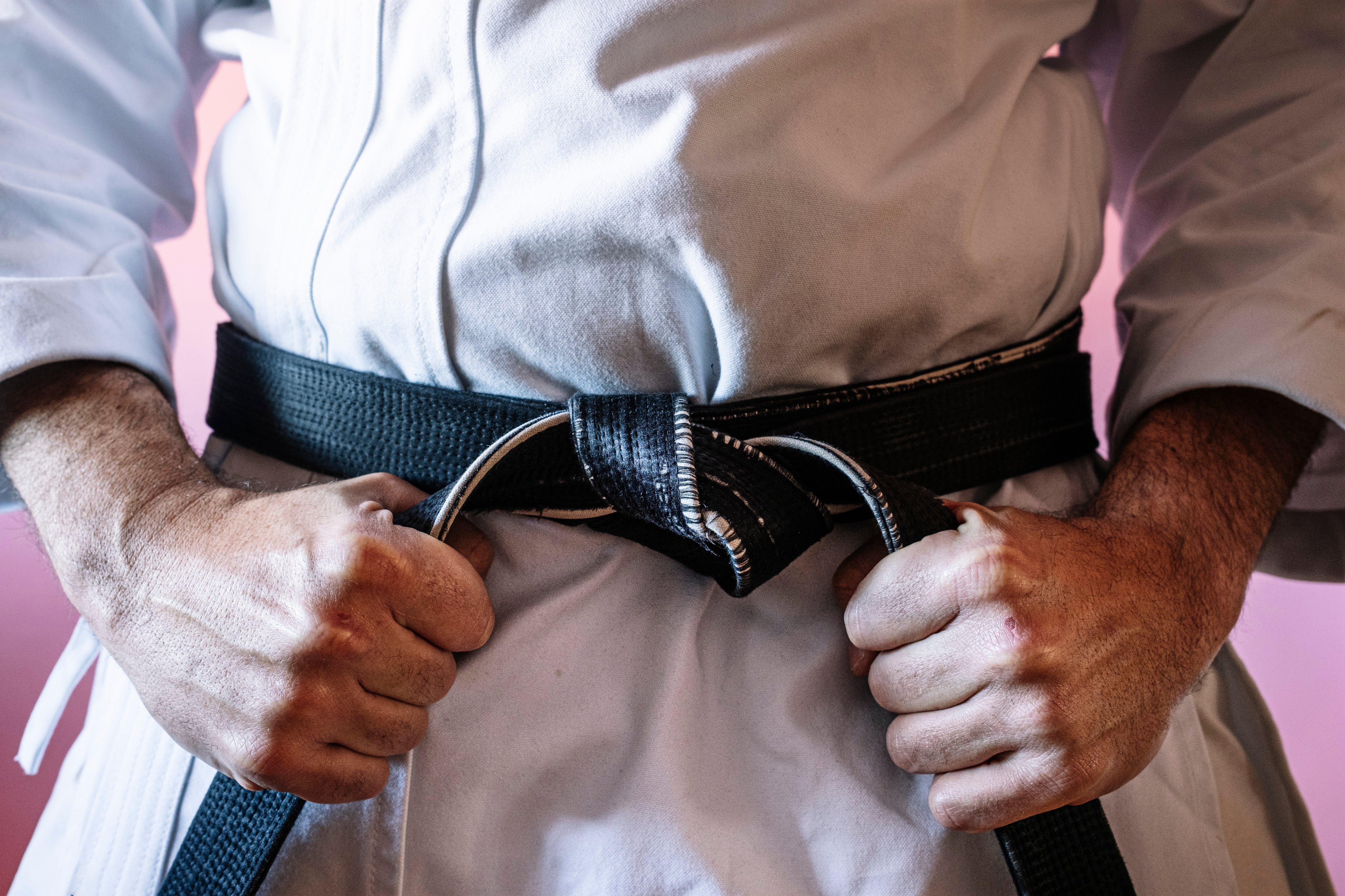 Unrecognizable karateka with black belt in firm position